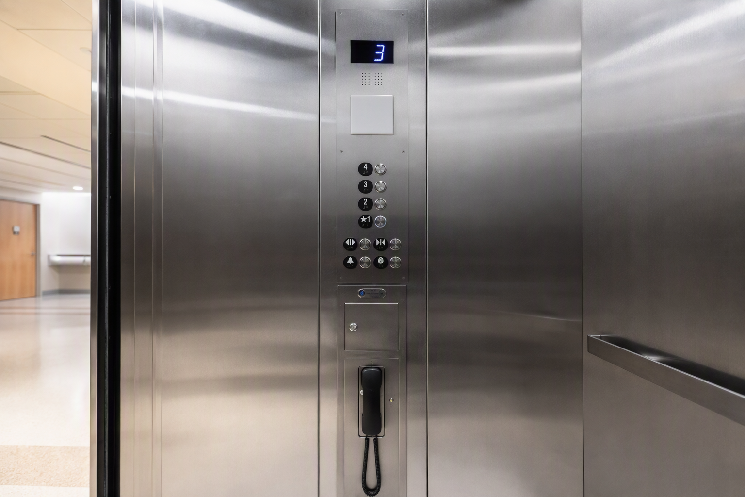 ADA-compliant hospital elevator cab interior showing tactile Braille control panel and emergency phone, illustrating healthcare elevator maintenance and accessibility standards inside a Houston medica