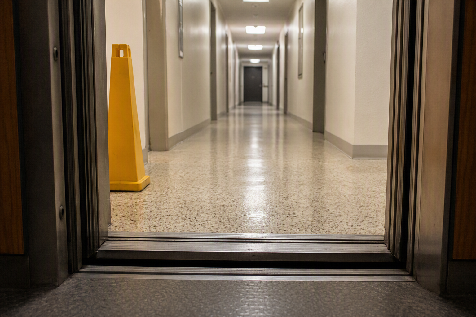 Elevator cab stopped several inches below the landing floor threshold in a San Antonio apartment building, illustrating a leveling system failure warning sign before full breakdown.